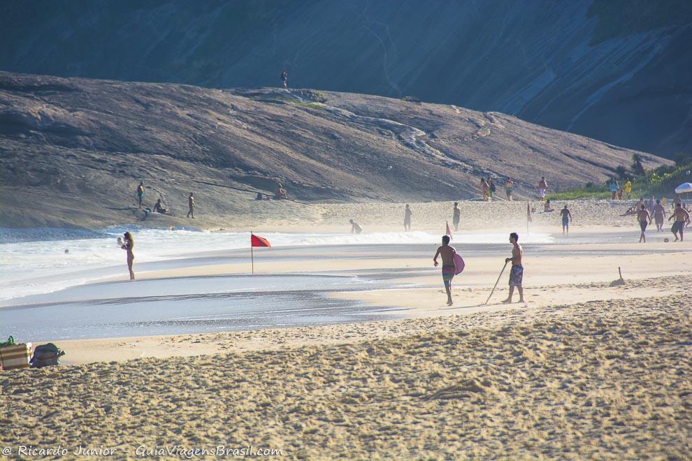 Imagem de adolescentes na beira da Praia de Itacoatiara, em Niterói.