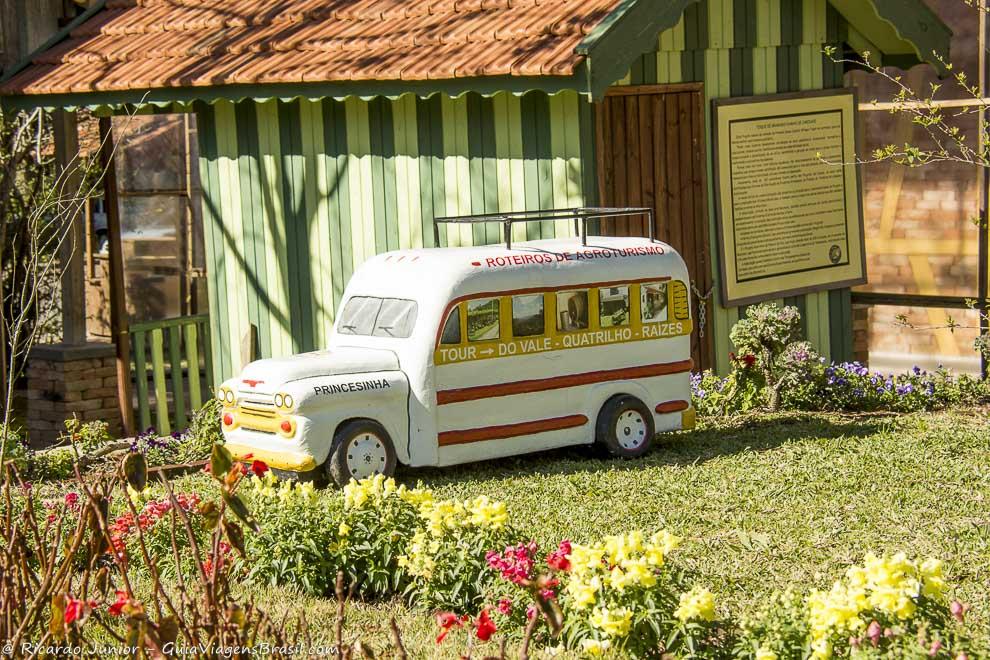 Imagem de uma casa de madeira com uma réplica de um ônibus do agroturismo.
