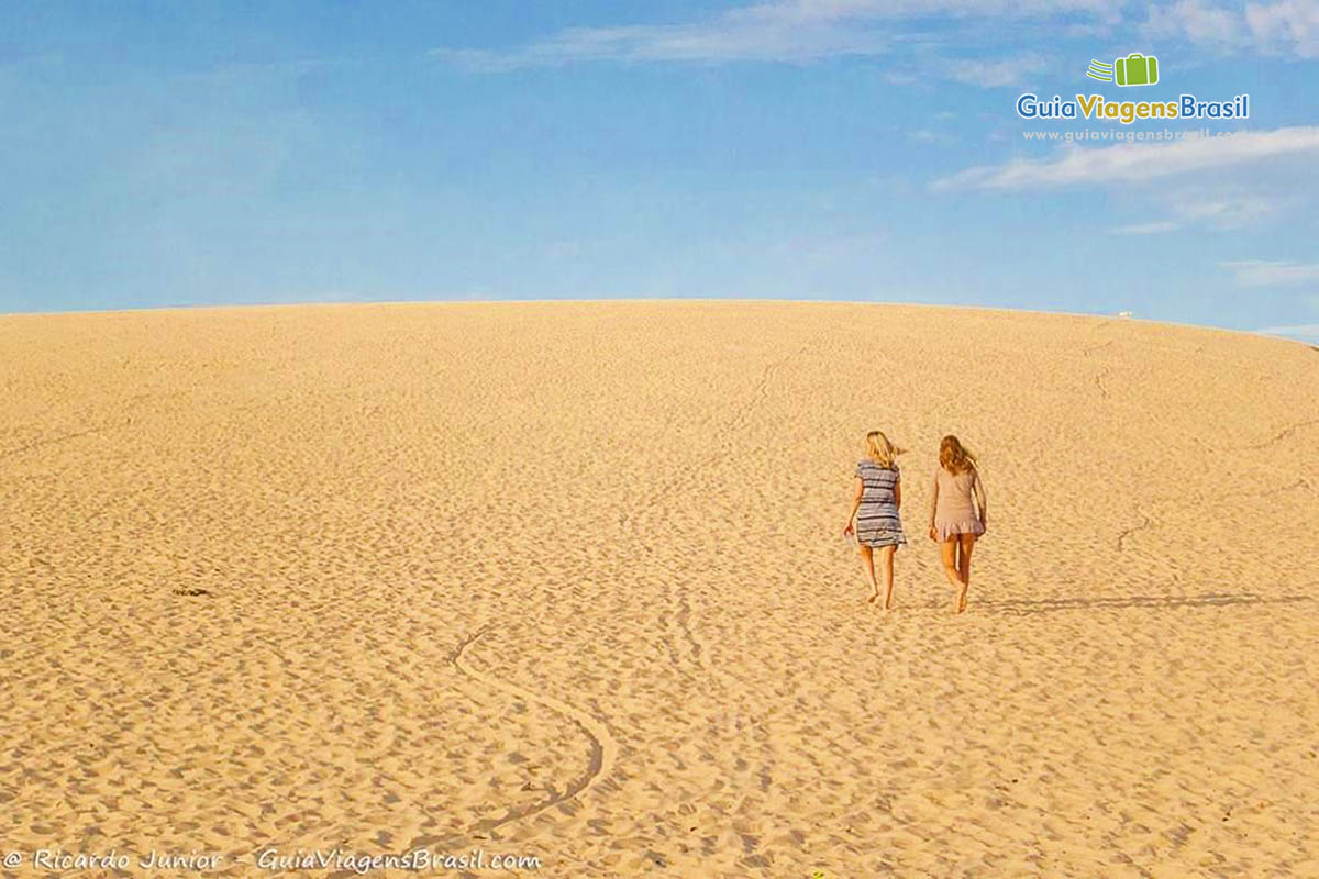 Imagem de duas amigas andando nas dunas da Praia de Jericoacoara.