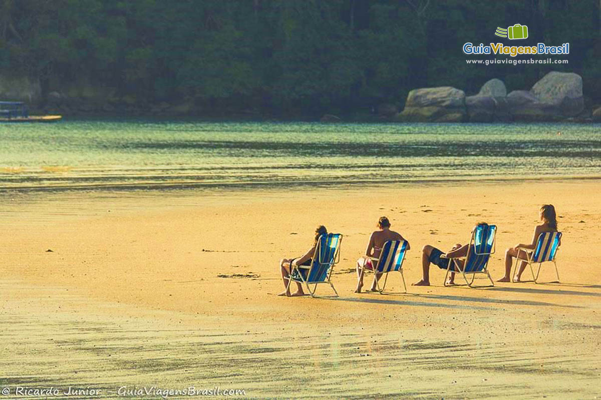 Imagem de amigos sentados na cadeira de praia aproveitando  o bela tarde.