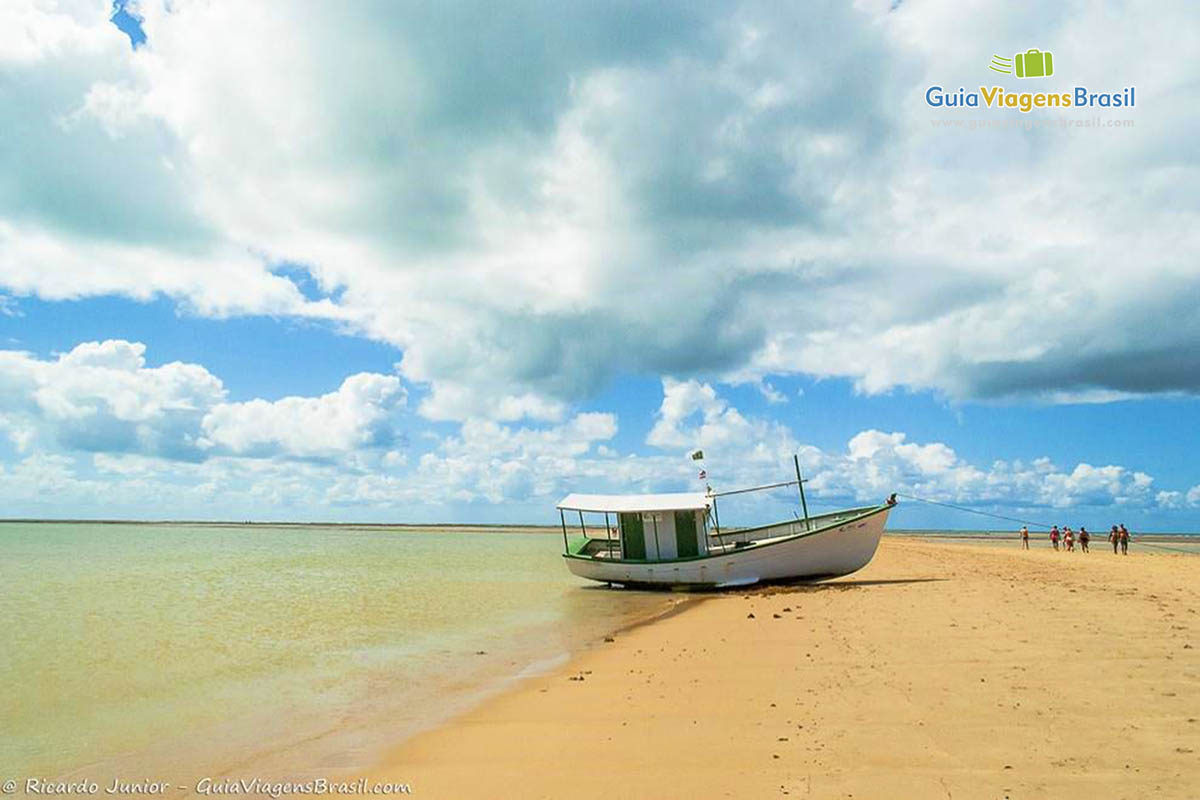 Imagem de um barco nas areias claras da linda praia.