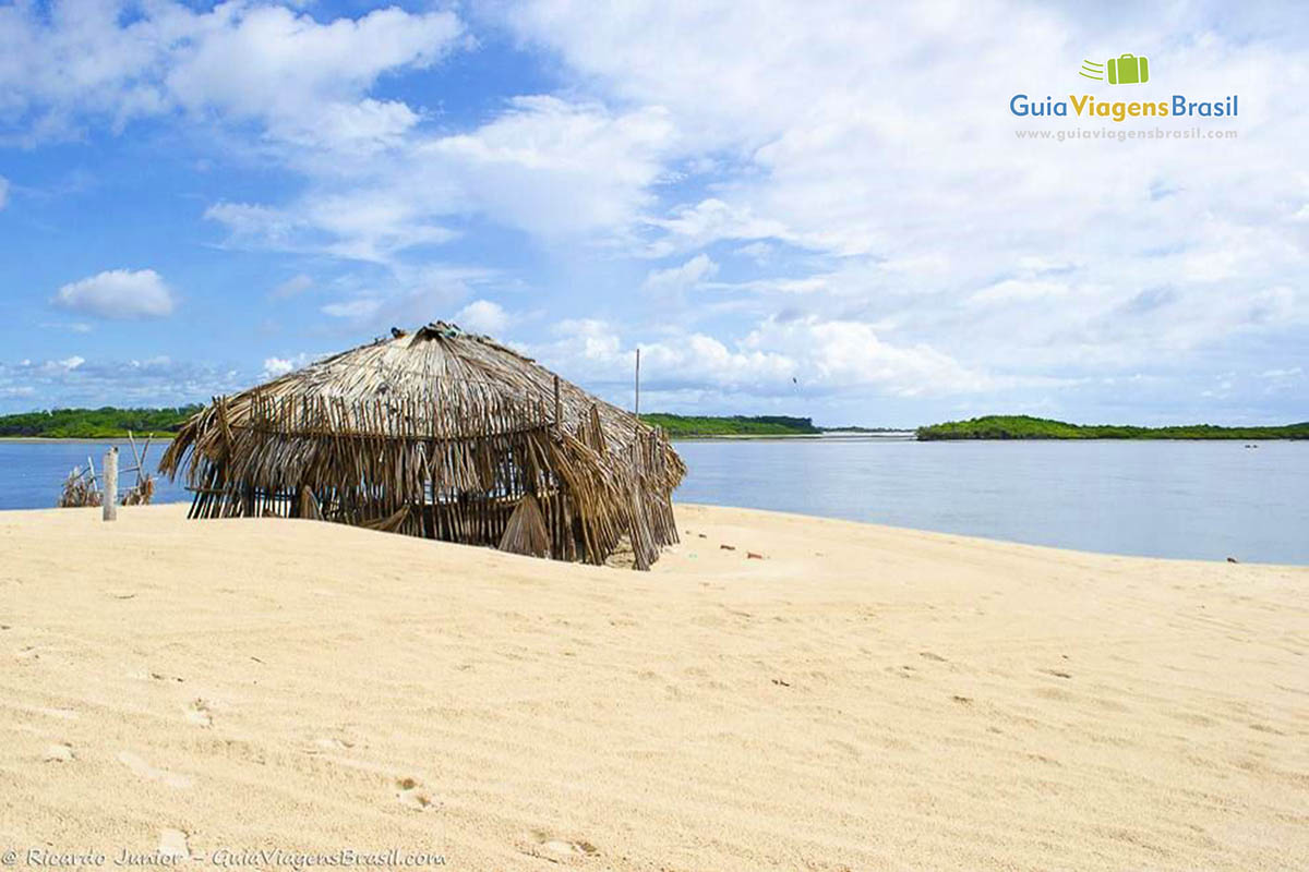 Imagem de uma barraca de bambu nas areias brancas.