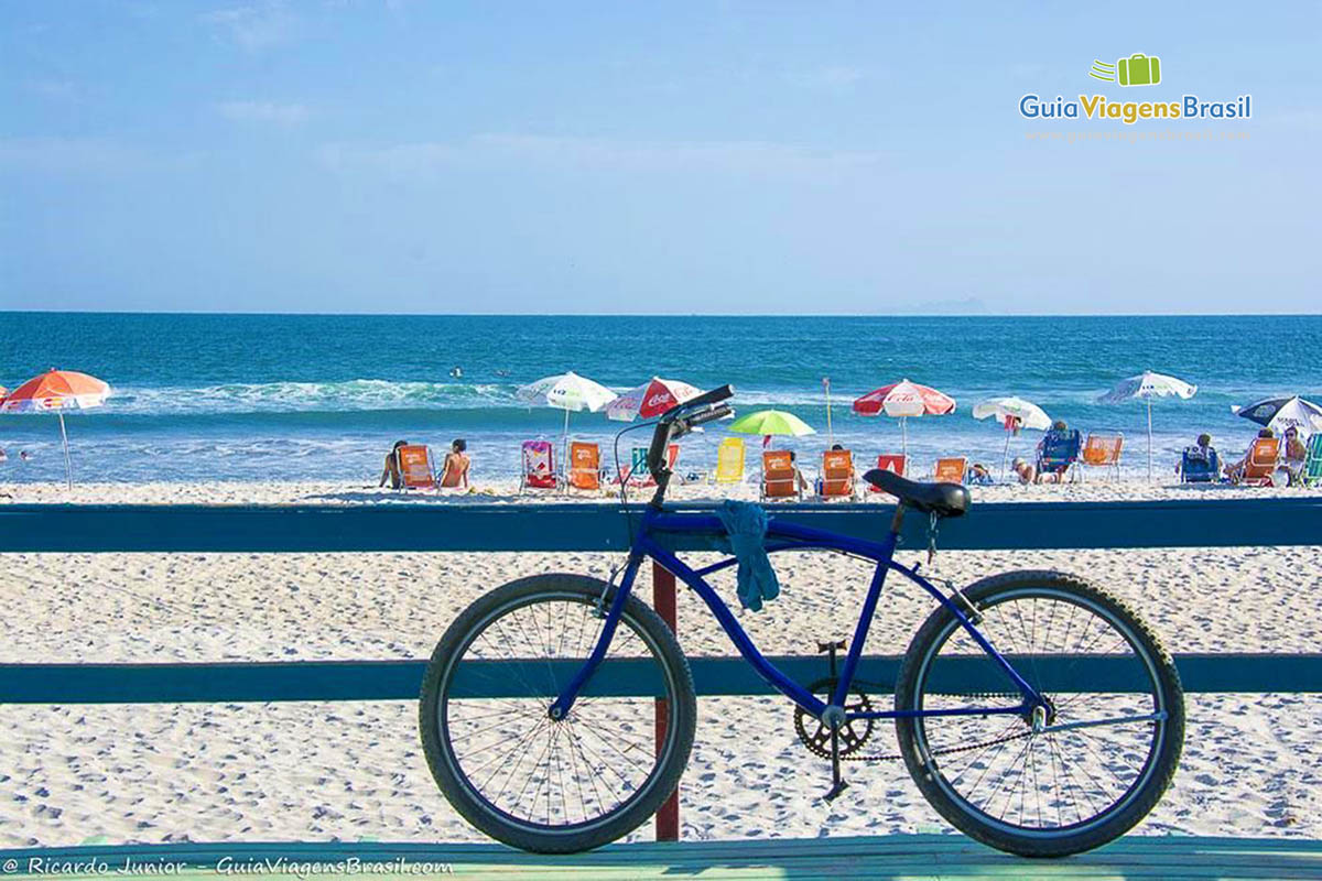 Imagem de bicicleta encostada  em uma grade na Praia Cambury.