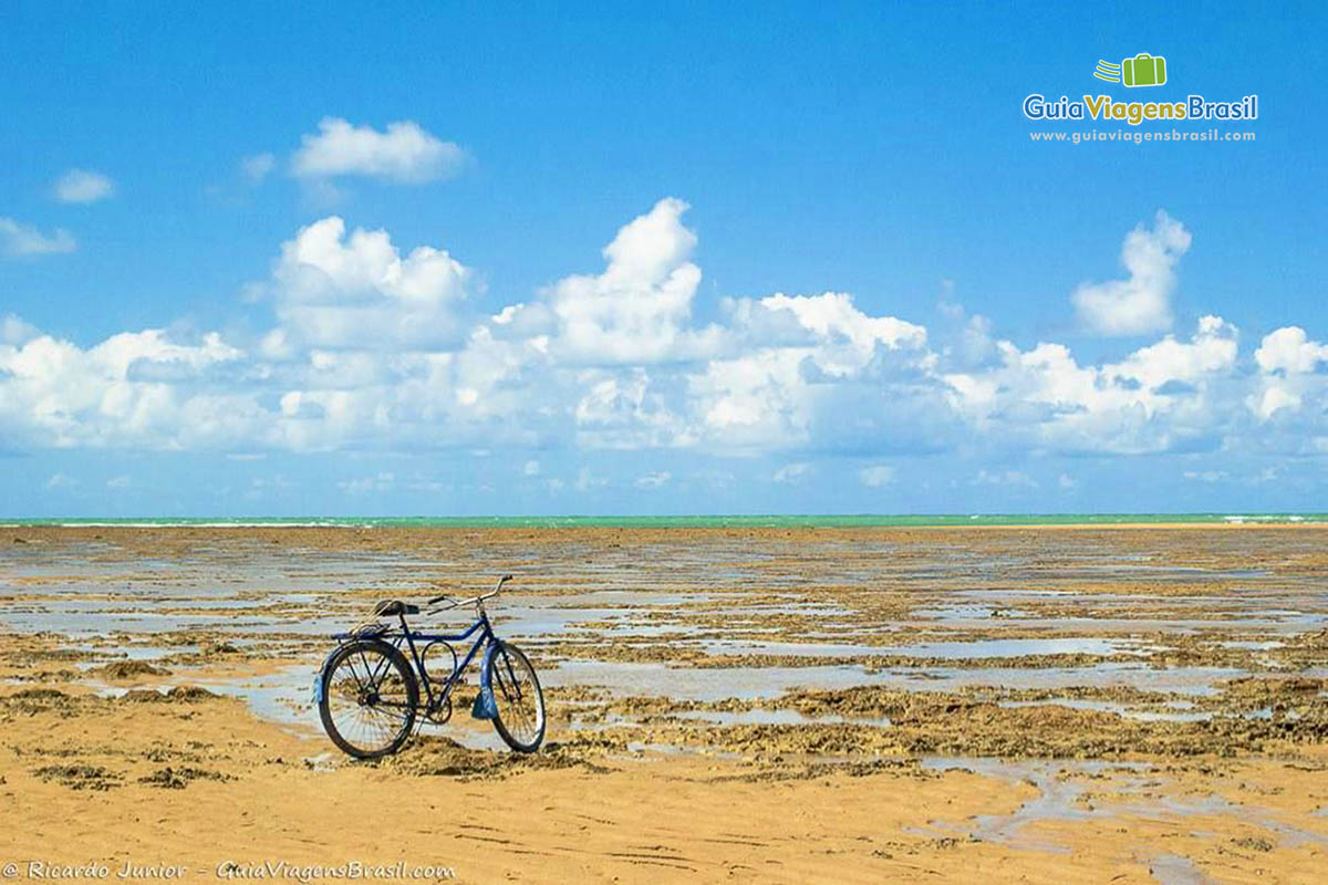 Imagem de uma bicicleta na areia da praia.