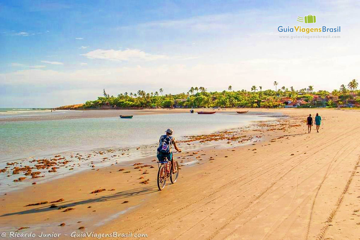 Imagem de pessoas caminhando e andando de bicicleta na praia.