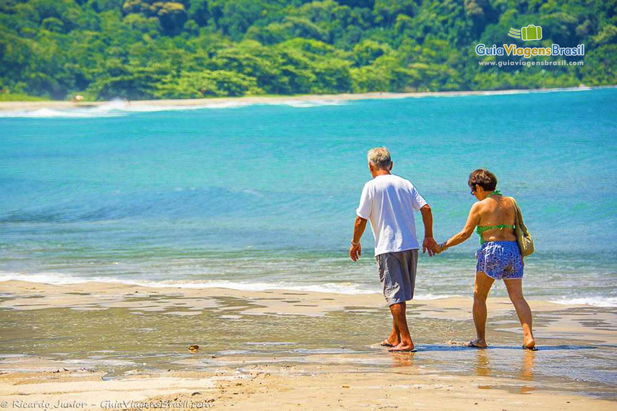 Imagem de casal andando na beira da Praia de Castelhanos.