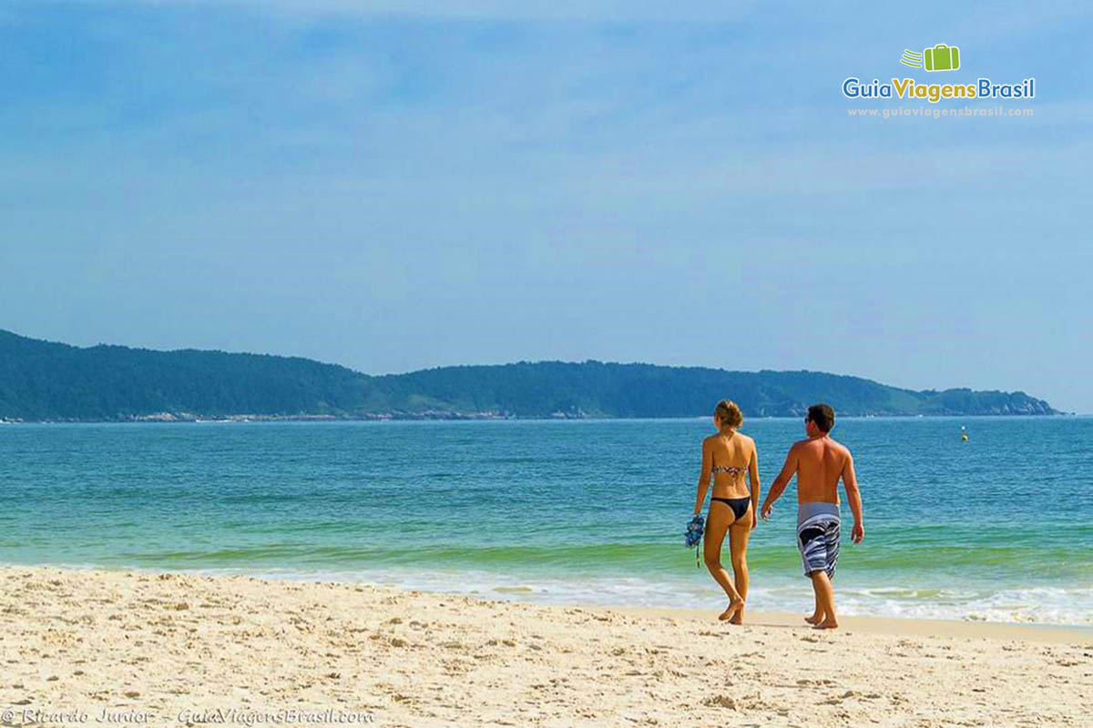 Imagem de casal andando nas areias da bela praia.