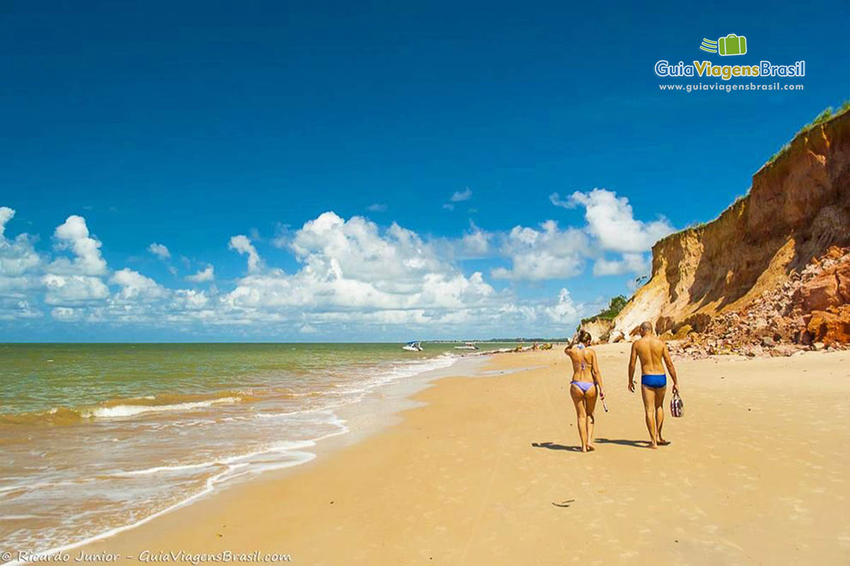 Imagem de casal andando tranquilamente pelas areias da Praia Carro Quebrado.