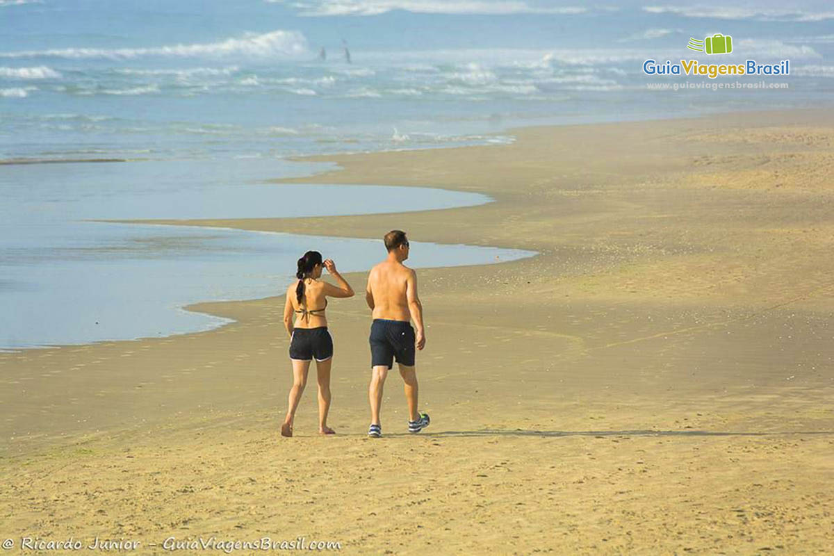 Imagem de um casal caminhando na praia.