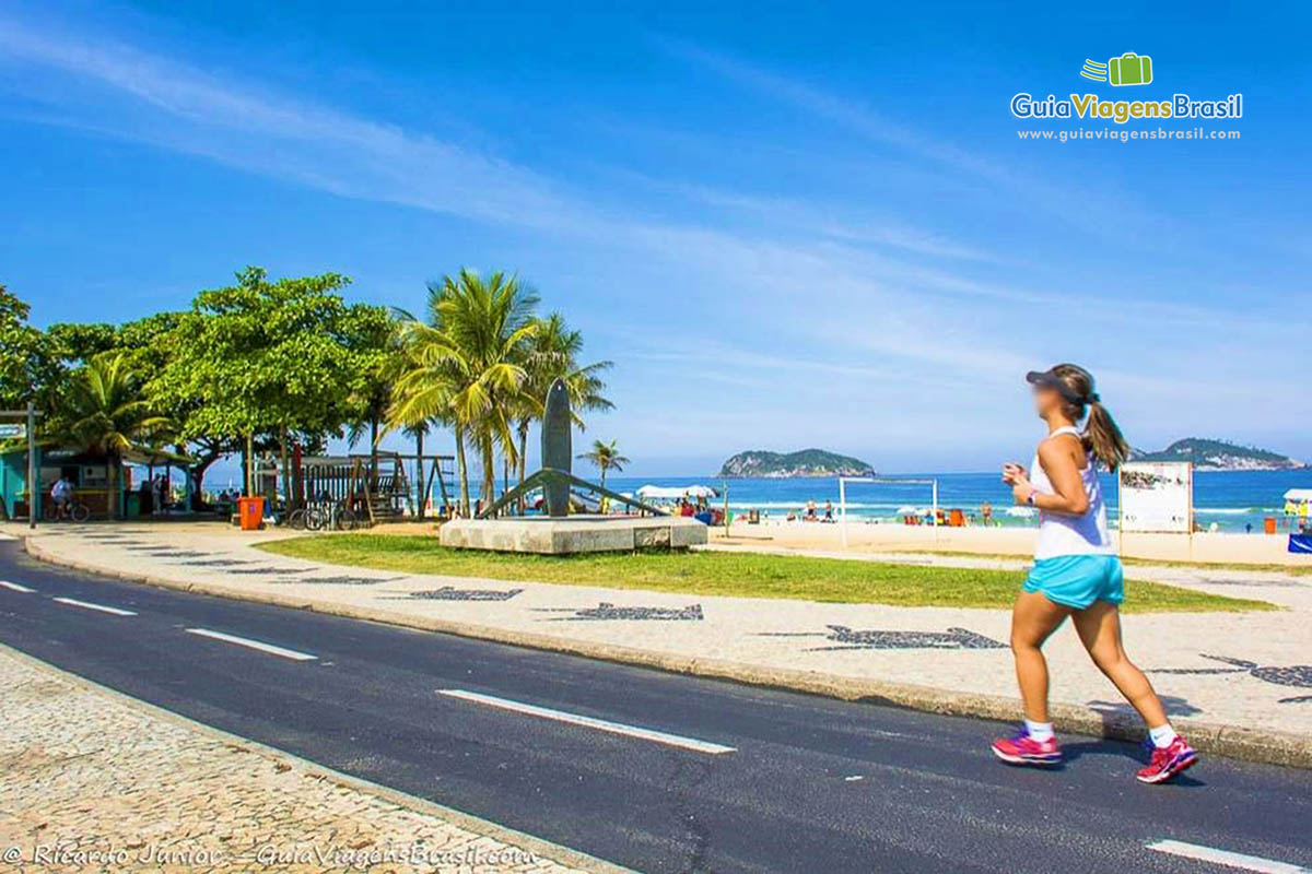 Imagem de uma moça correndo na orla da linda praia.