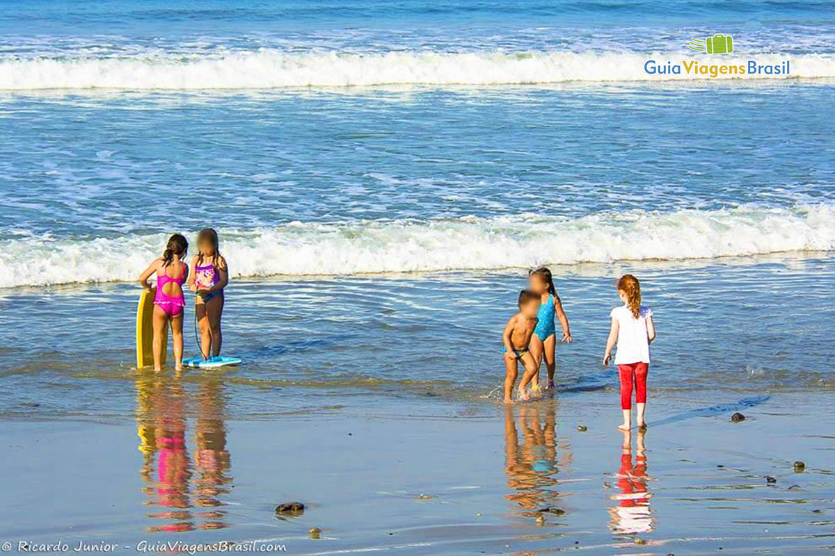 Imagem de crianças na beira do mar da linda Praia das Toninhas.