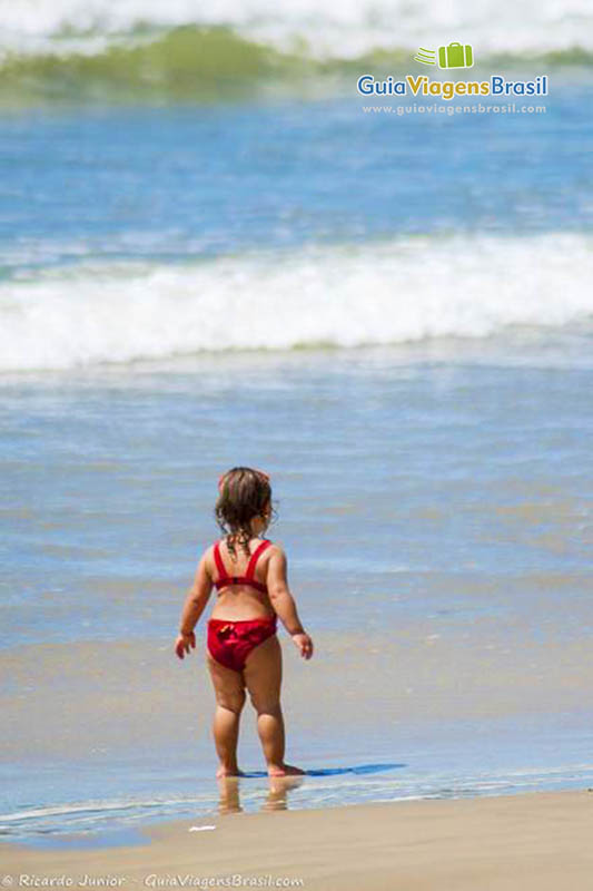 Imagem de uma menina na beira da praia.