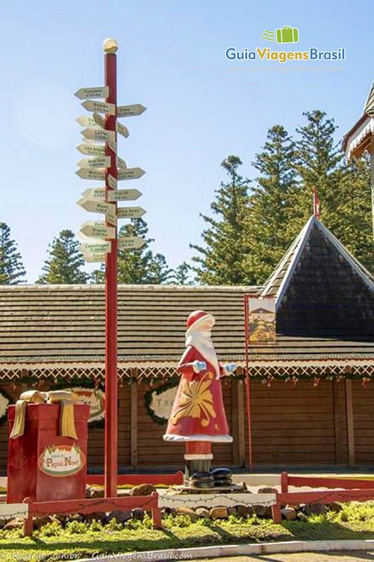 Imagem de réplica Papai Noel e placas indicando caminho aos seus visitantes.