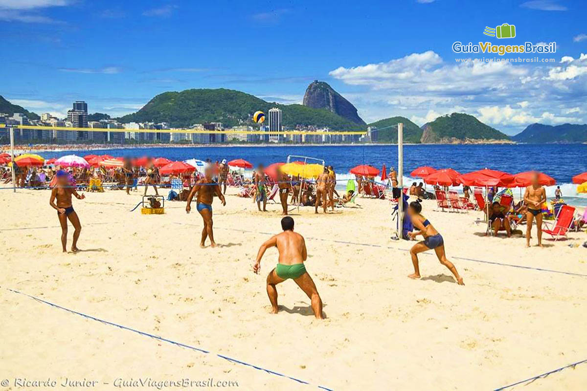 Imagem de meninos e meninas praticando vôlei na praia.