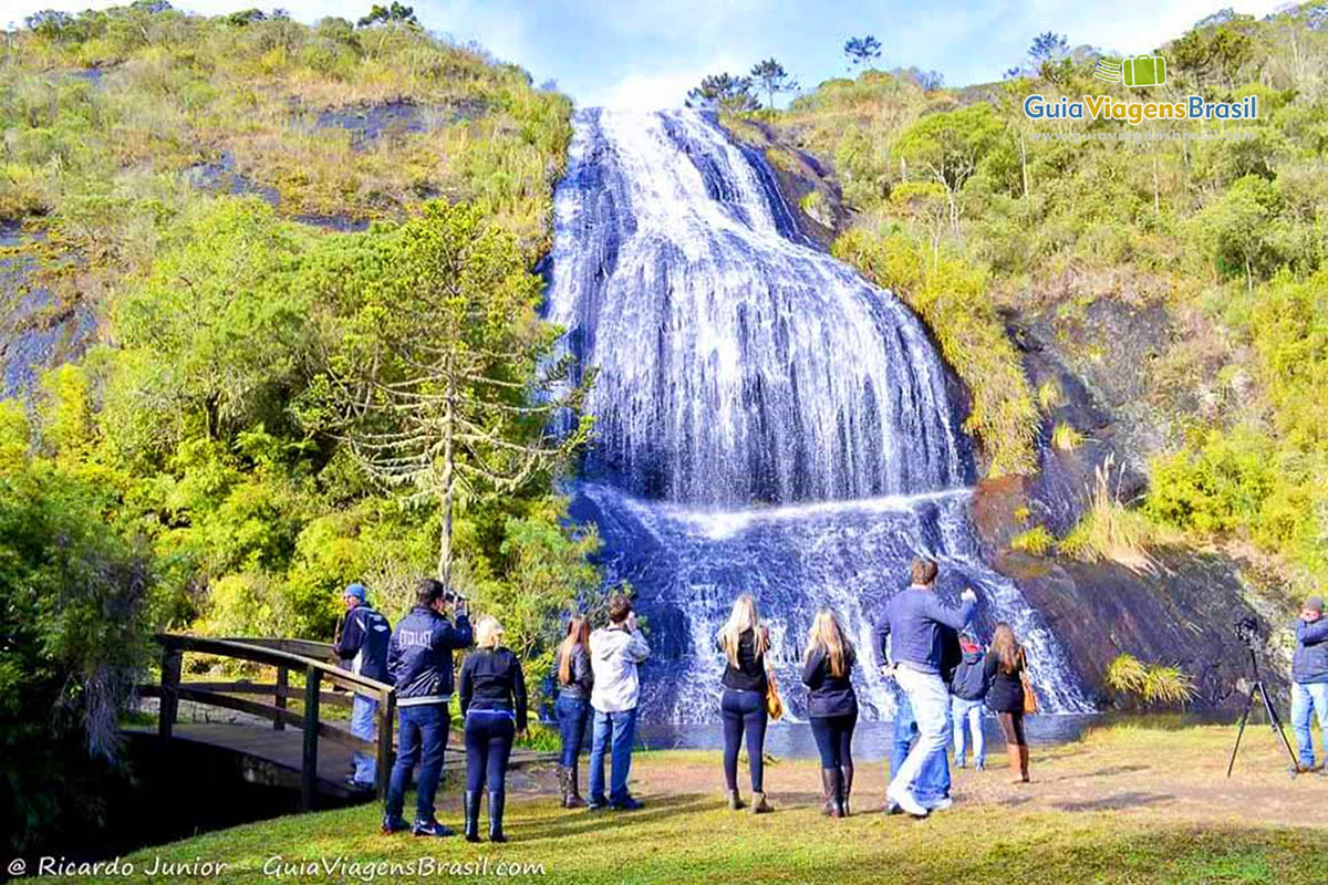 Imagem de turistas fotografando a bela cascata, na serra catarinense.