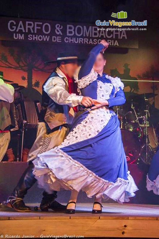 Imagem de casal dançando com bela roupas típicas.