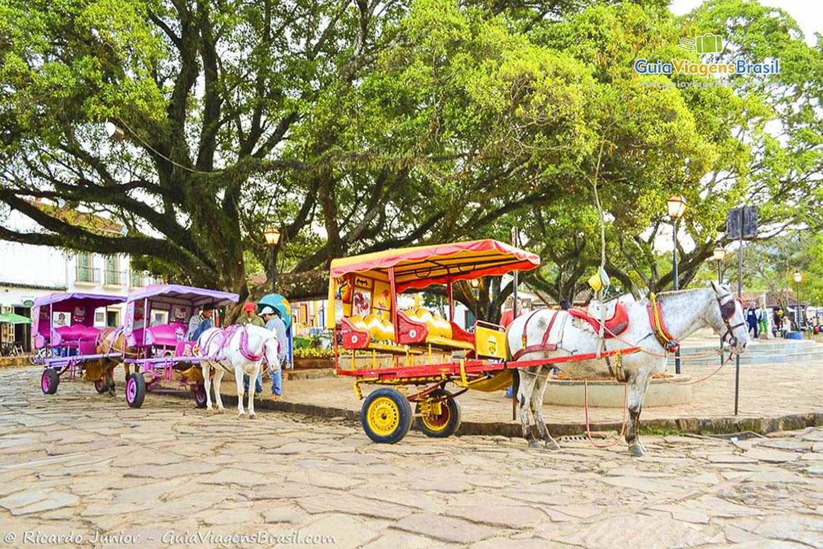 Imagem do Largo das Forras com charretes na praça e comério da cidade de Tiradentes.