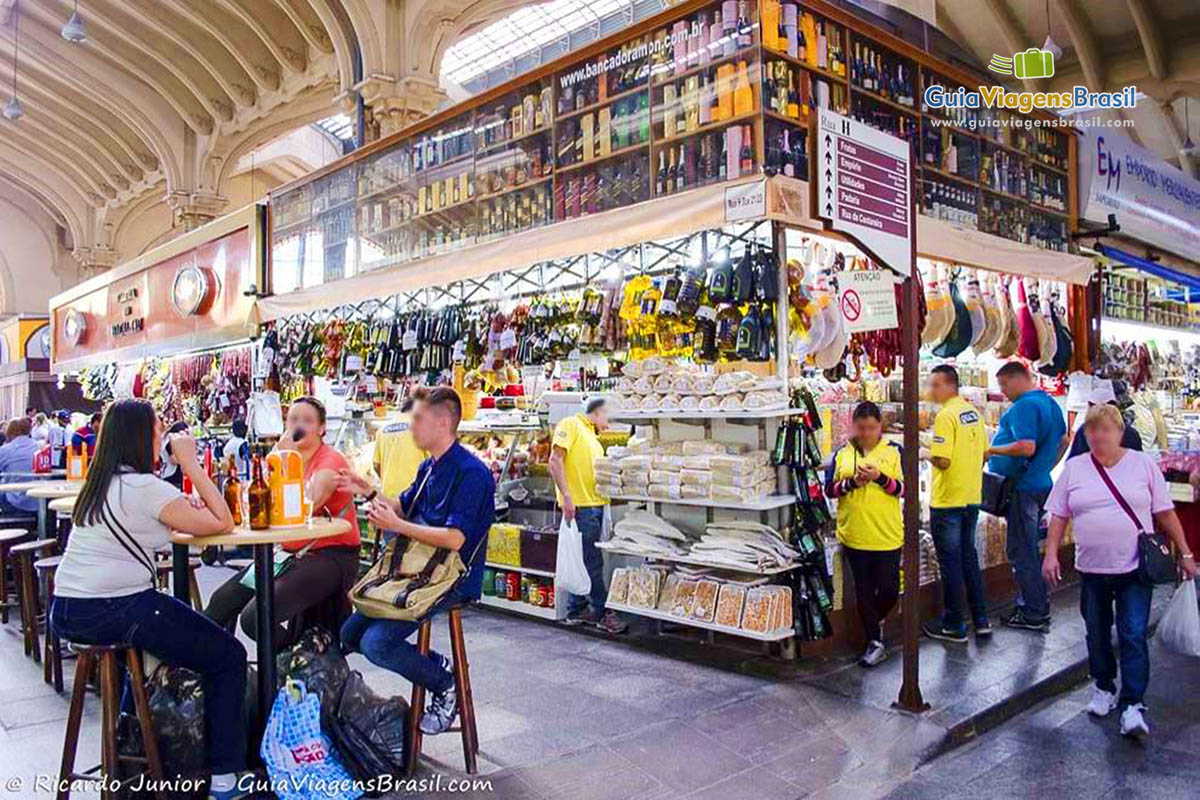 Imagem de pessoas na mesinha das lojas no Mercado Municipal, em São Paulo.