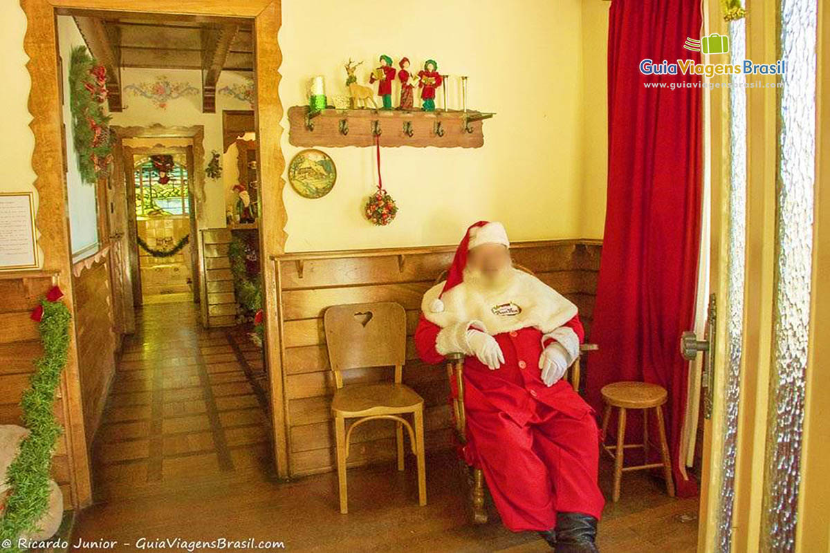 Imagem do Papai Noel sentado na entrada de sua casa.