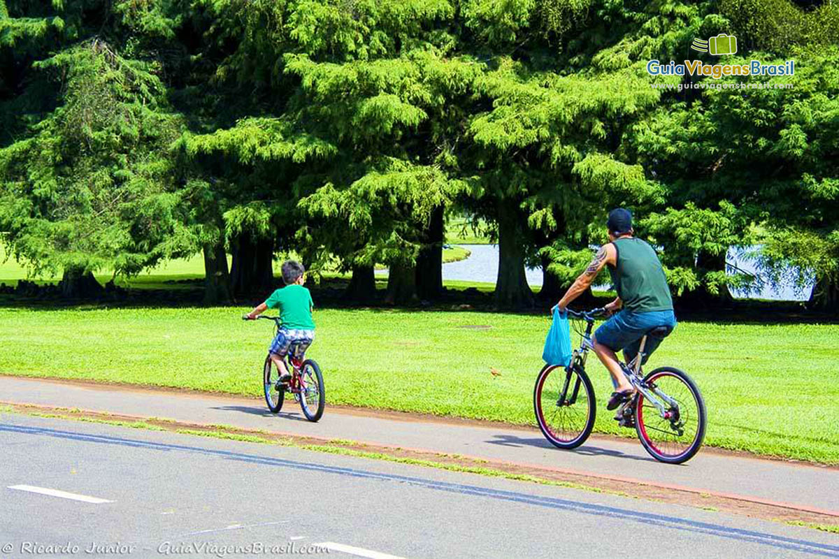 Imagem de pai e filho curtindo um passeio de bicicleta.