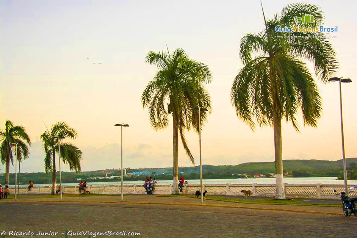 Imagem de moradores sentados no murinho nas margens do rio, em Penedo, Alagoas, Brasil. 