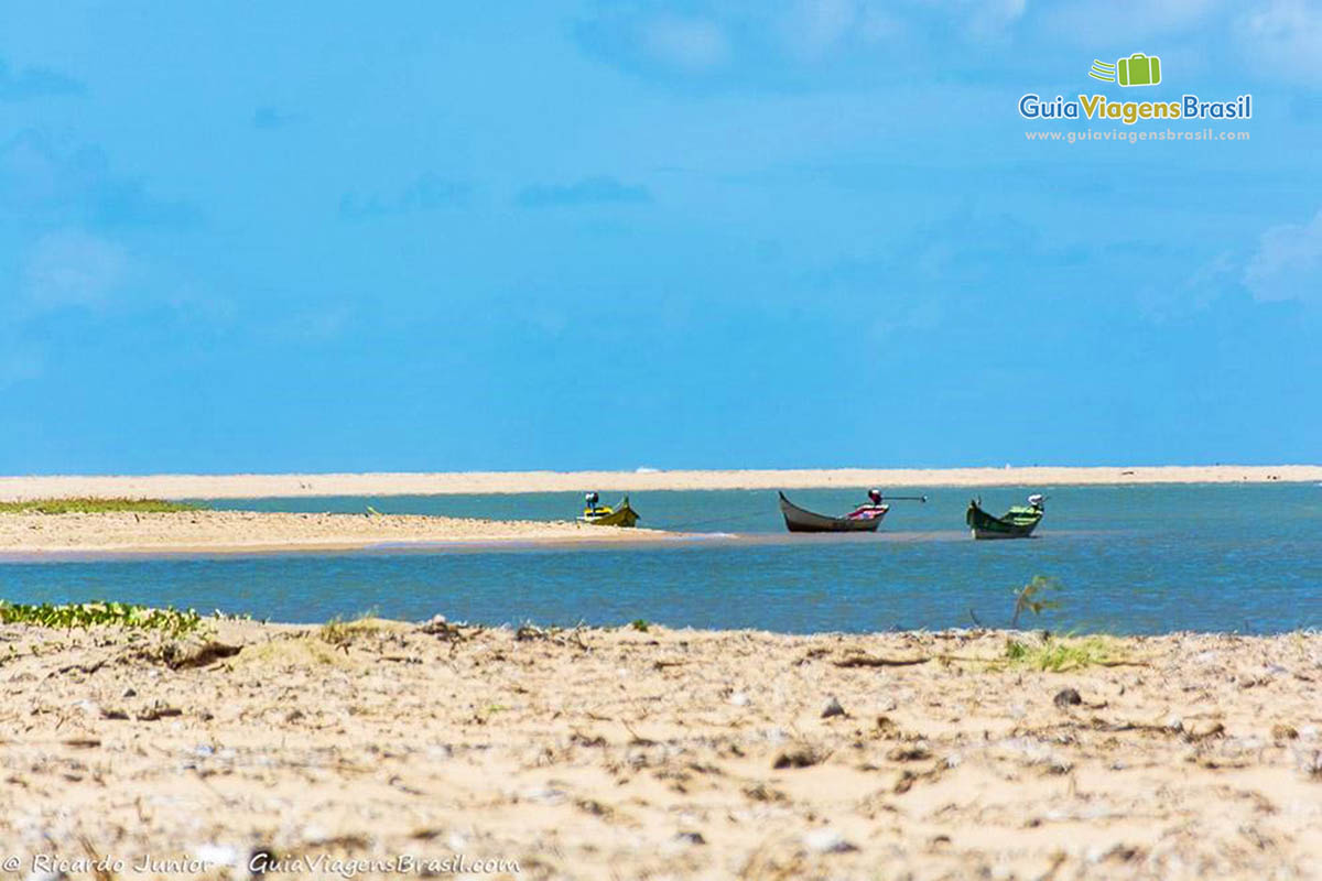 Imagem bela da areia e três barcos de pescador parados nas águas cristalinas de Foz Rio São Francisco, em Alagoas, Brasil.