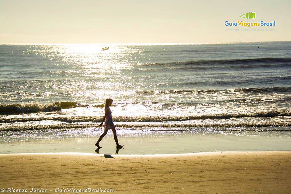 Imagem de menina caminhando na Praia de Itapoá, com uma luz do sol maravilhosa, em Santa Catarina, Brasil.