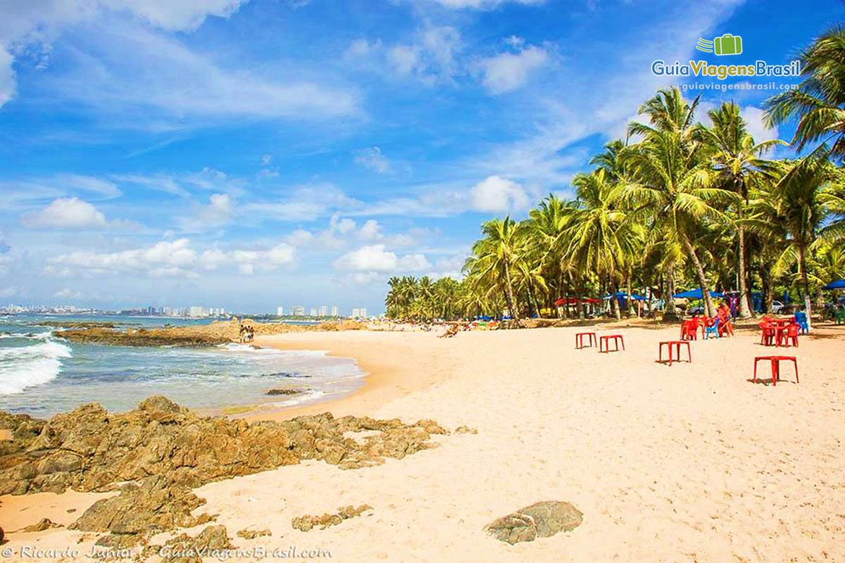 Imagem da ponta da Praia de Itapuã, com mesas e cadeiras a disposição dos turistas.