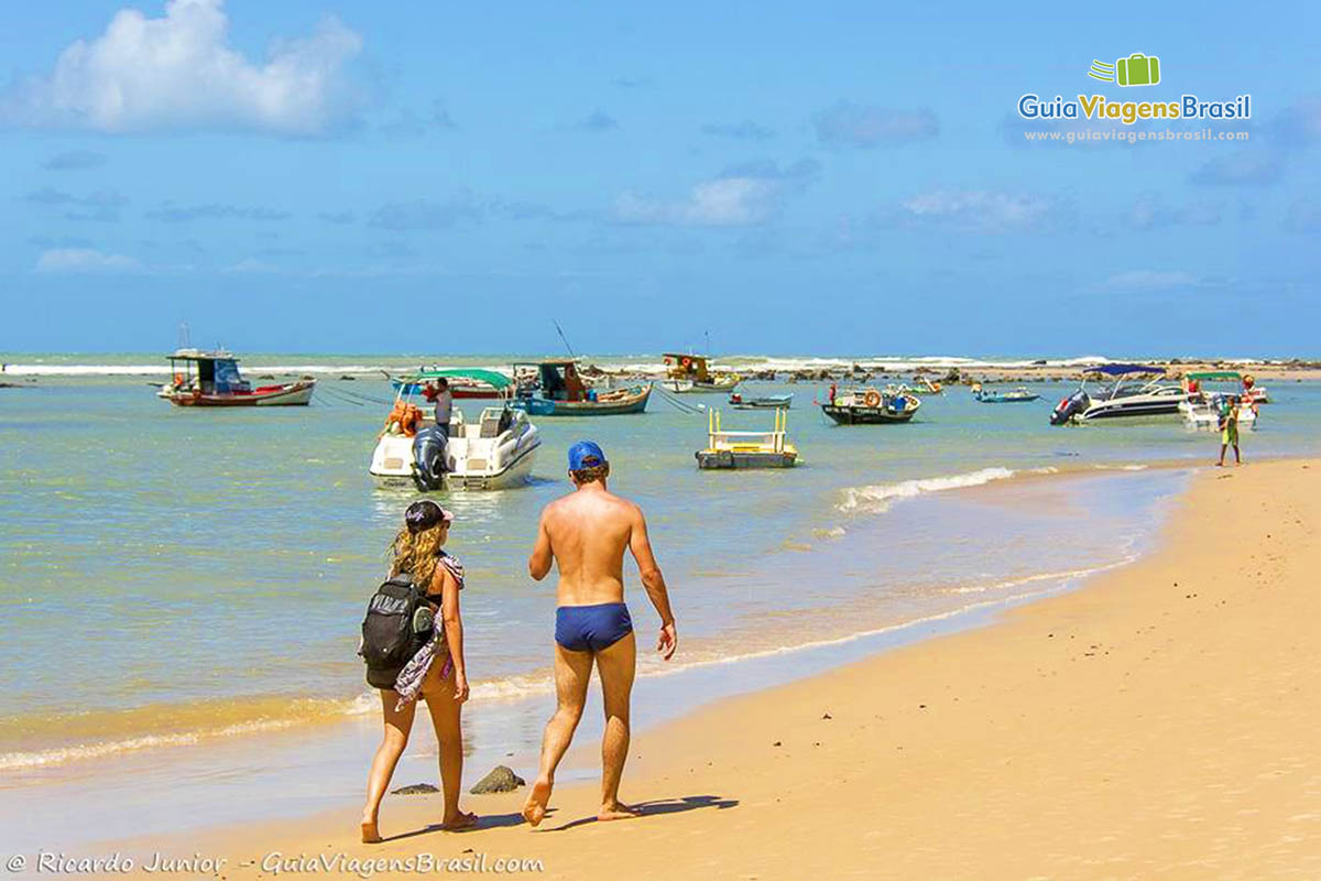 Imagem de turistas na praia de ao fundo os barcos na Praia de Pipa.