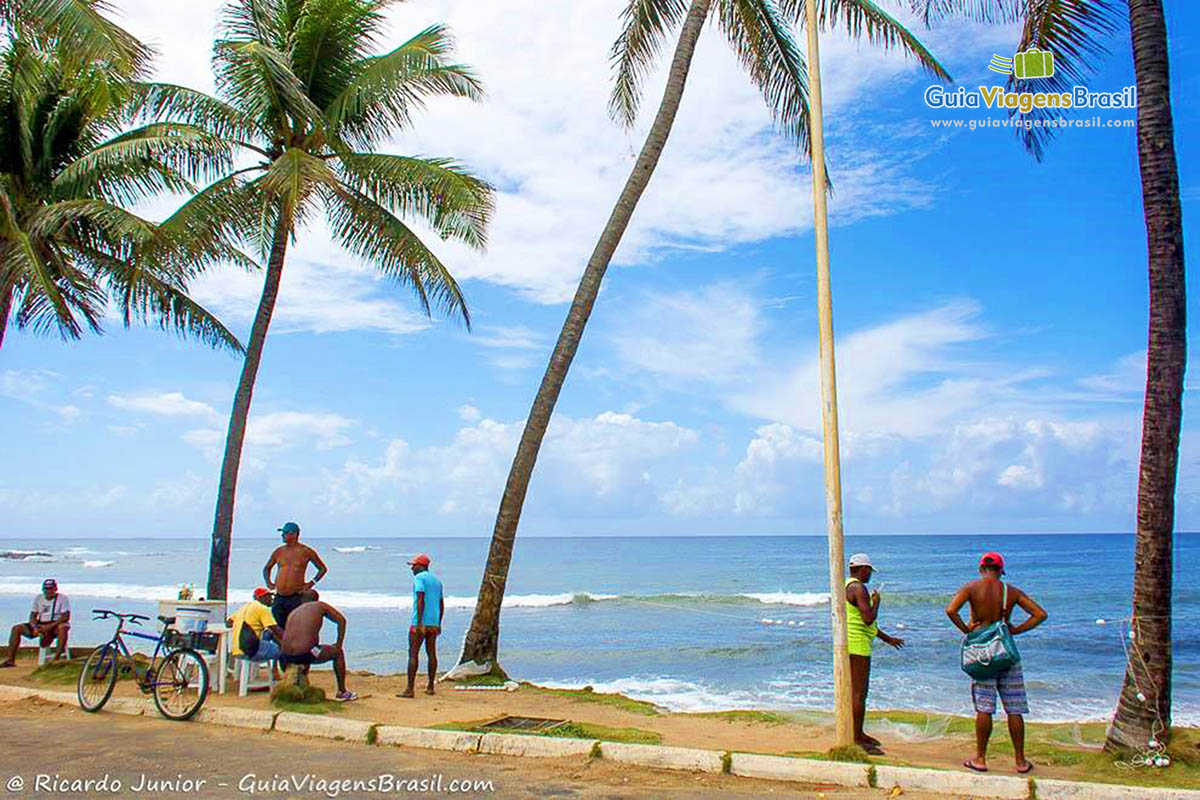 Imagem de pessoas na orla da praia conversando e admirando a Praia de Pituba, em Salvador.