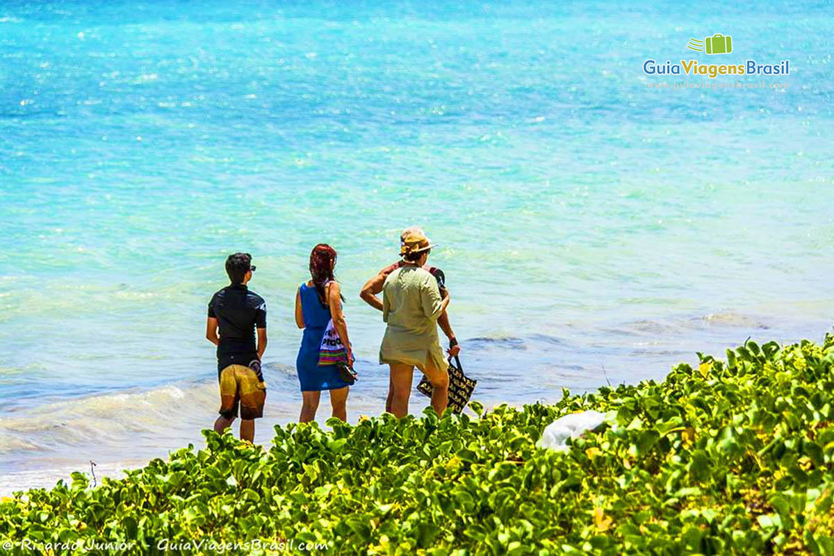 Imagem de três turistas admirando a Praia de Ponta Verde em Maceió, Alagoas, Brasil.