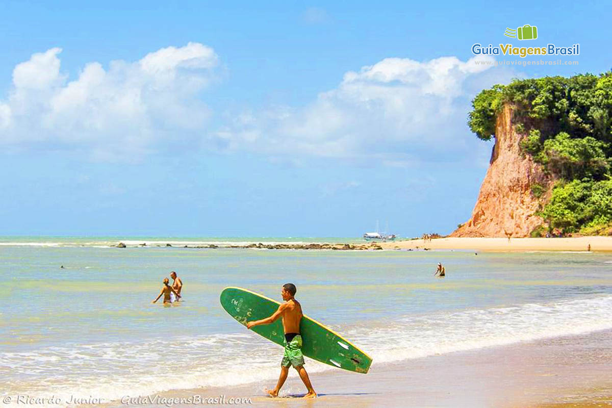 Imagem de surfista entrando no mar, na Praia do Curral.