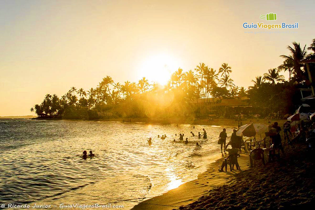 Imagem da Praia do Forte, turistas aproveitando os últimos minutos de sol.