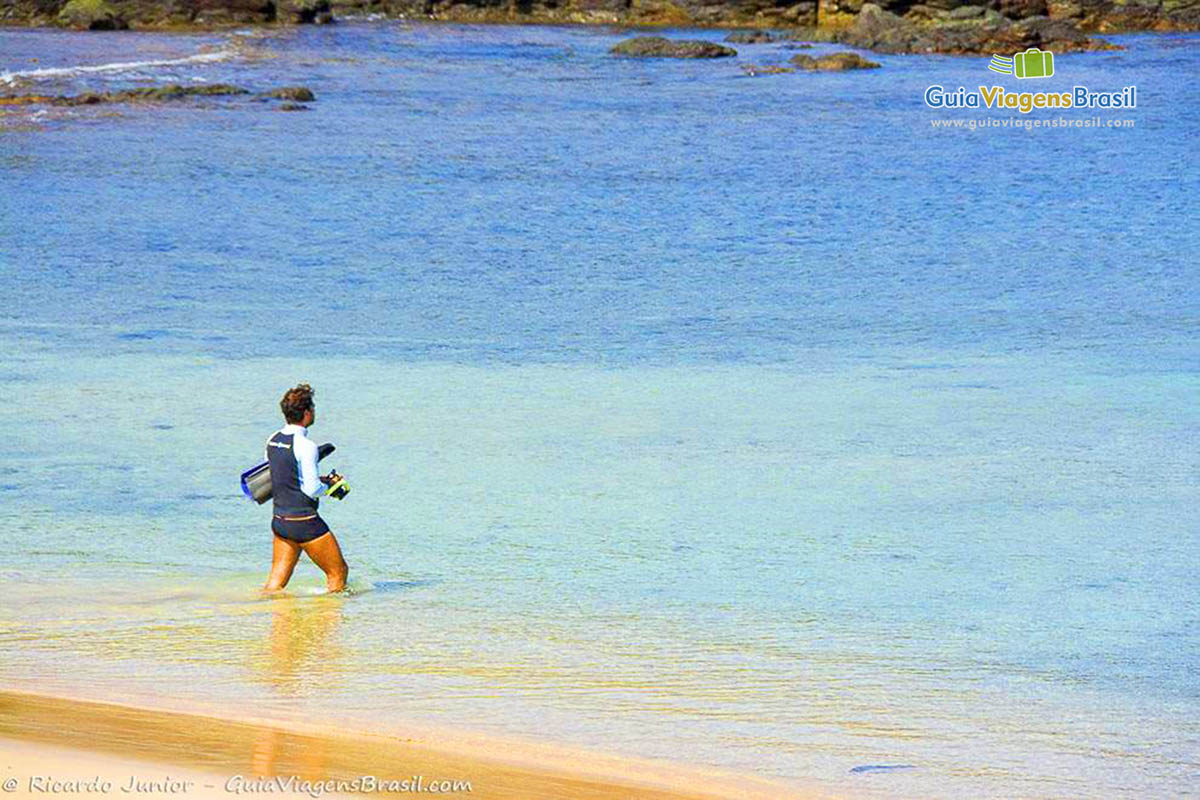 Imagem de turista entrando no mar com seu equipamento para mergulho, em Fernando de Noronha, Pernambuco, Brasil.