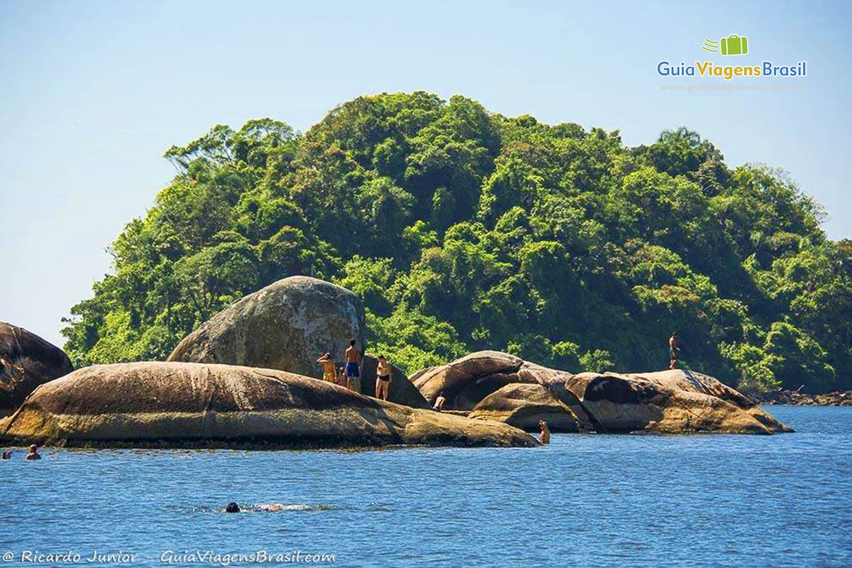 Imagem de turistas nas pedras da Praia Mansa, em Caiobá, Santa Catarina, Brasil.