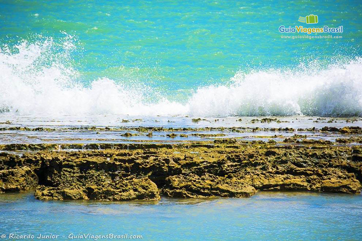 Imagem de Pontal do Coruripe, as águas claras do mar batendo nas pedras, em Alagoas, Brasil.