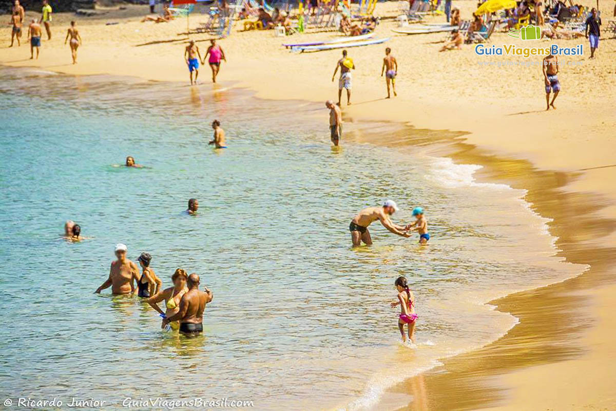 Imagem de famílias nadando nas águas claras da Praia Porto da Barra.