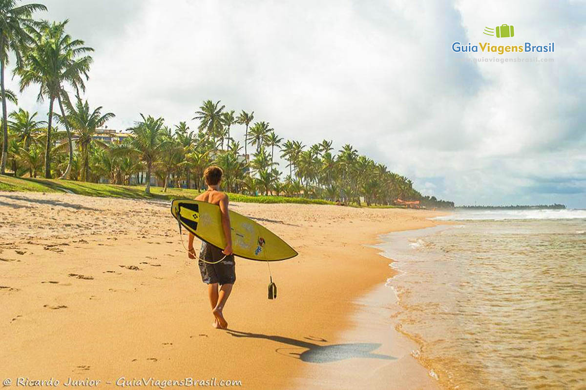 Imagem de surfista andando nas areias da Praia Vilas do Atlântico.