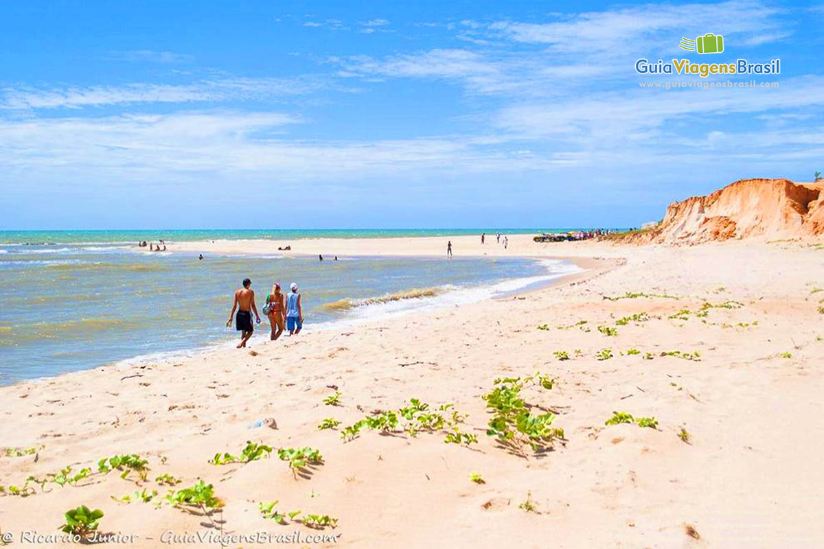 Imagem de amigos chegando e caminhando pelas areias brancas da Praia Canoa Quebrada.