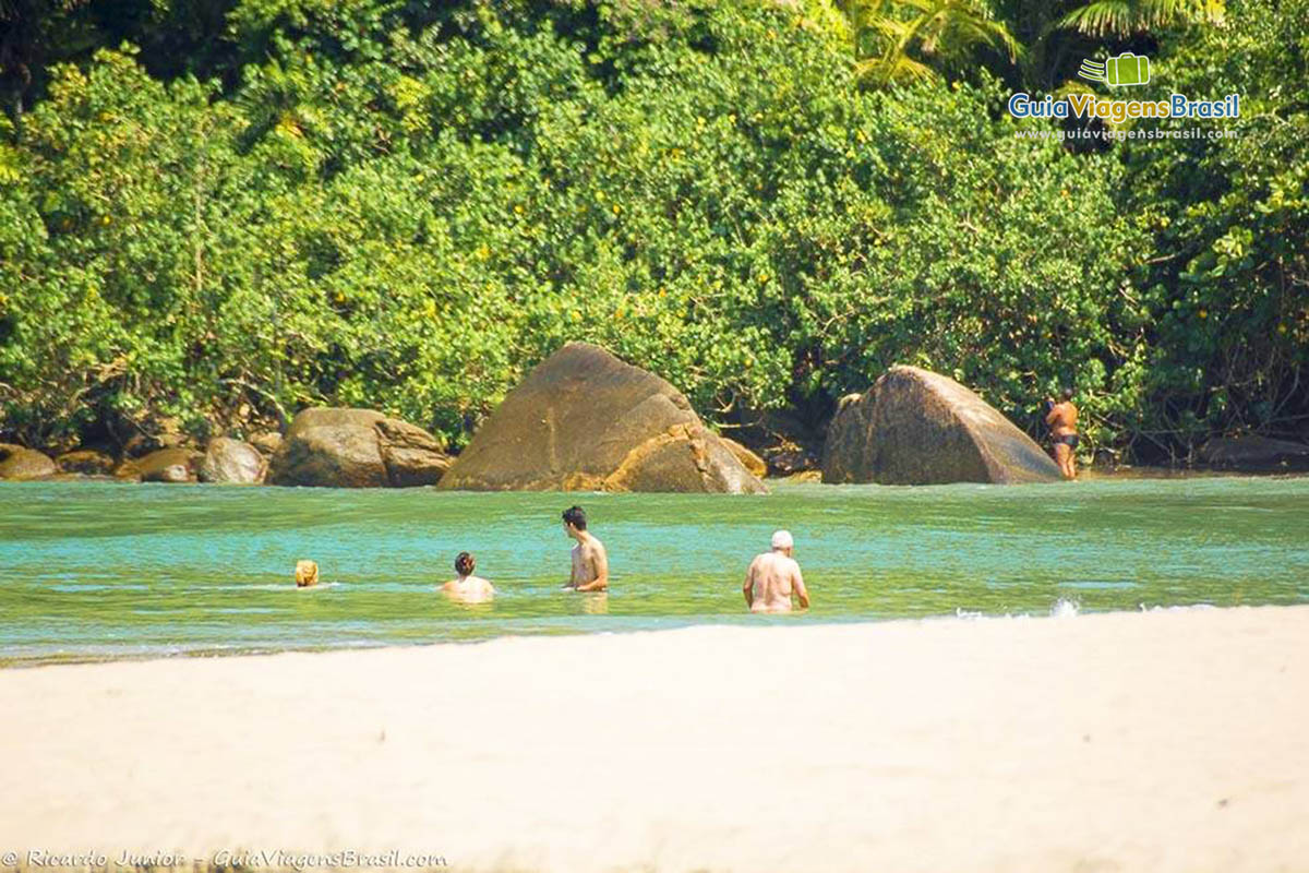 Imagem de pessoas nas águas azuis da Praia de Castelhanos.