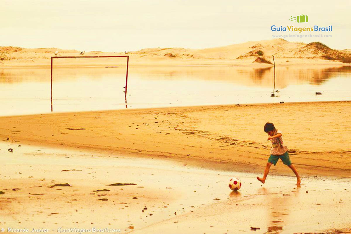 Imagem de um menino jogando bola nas águas da Guarda do Embaú.