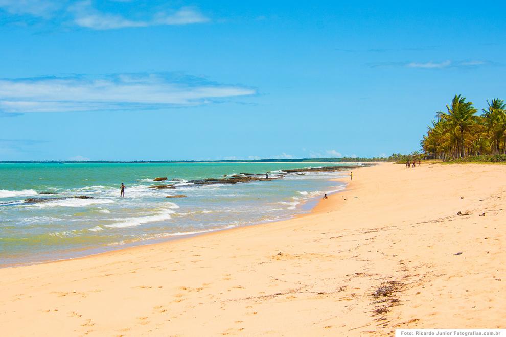 A bela praia de Caraíva com mar azul, coqueiros e areia fofa emoldurada por coqueiros.