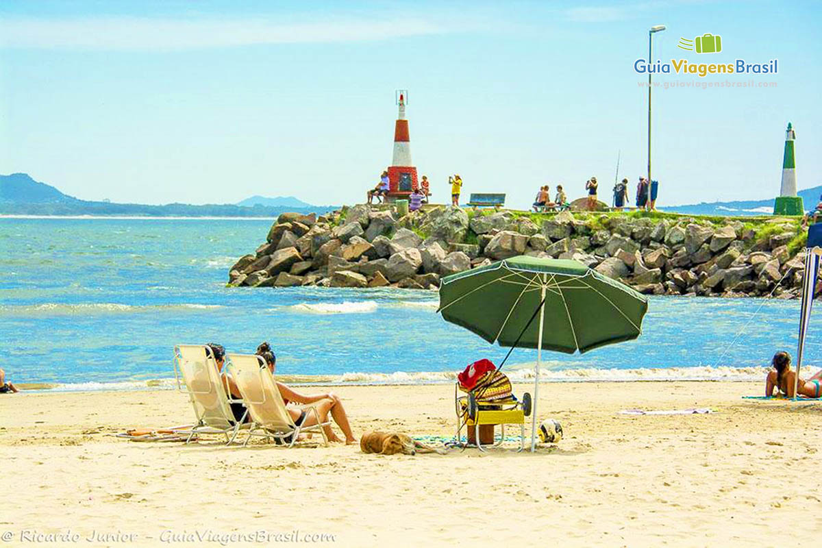 Imagem de turistas admirando a bela Praia Barra da Lagoa, em Florianópolis.