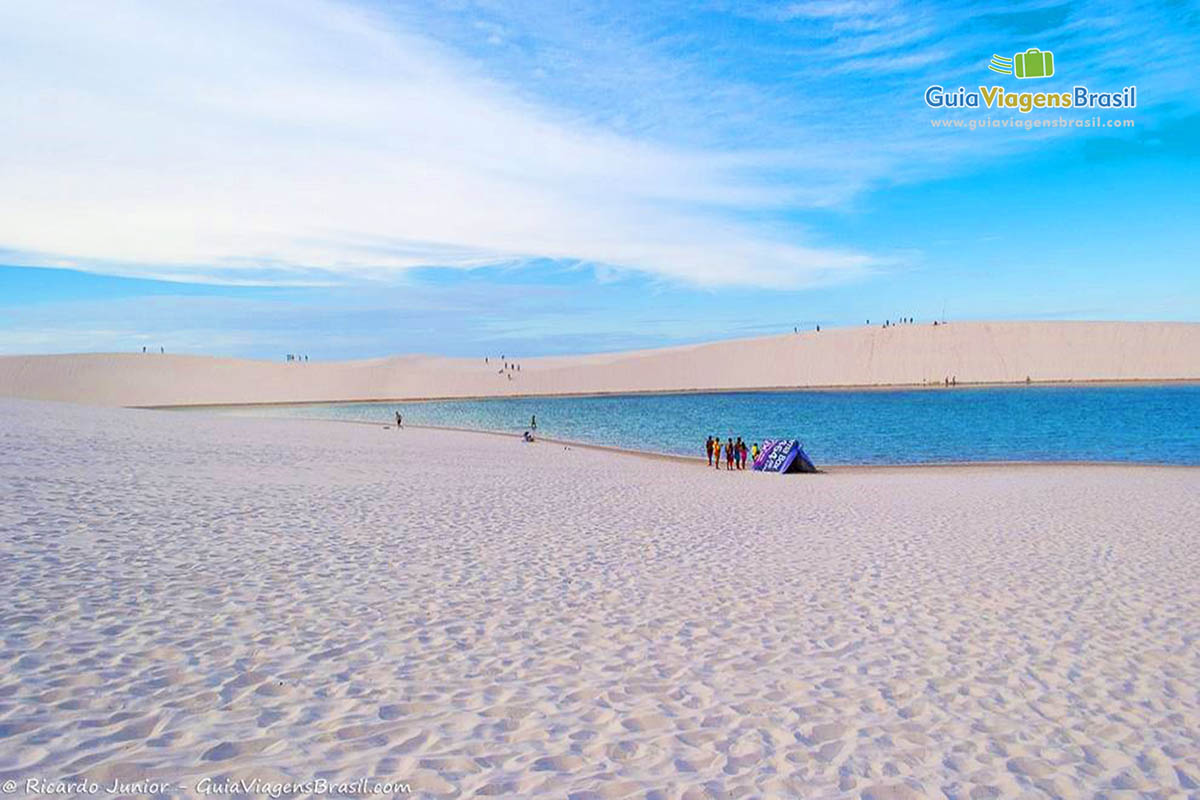 Imagem das águas e ao longe os turistas sobre as dunas no Circuito Lagoa Azul.