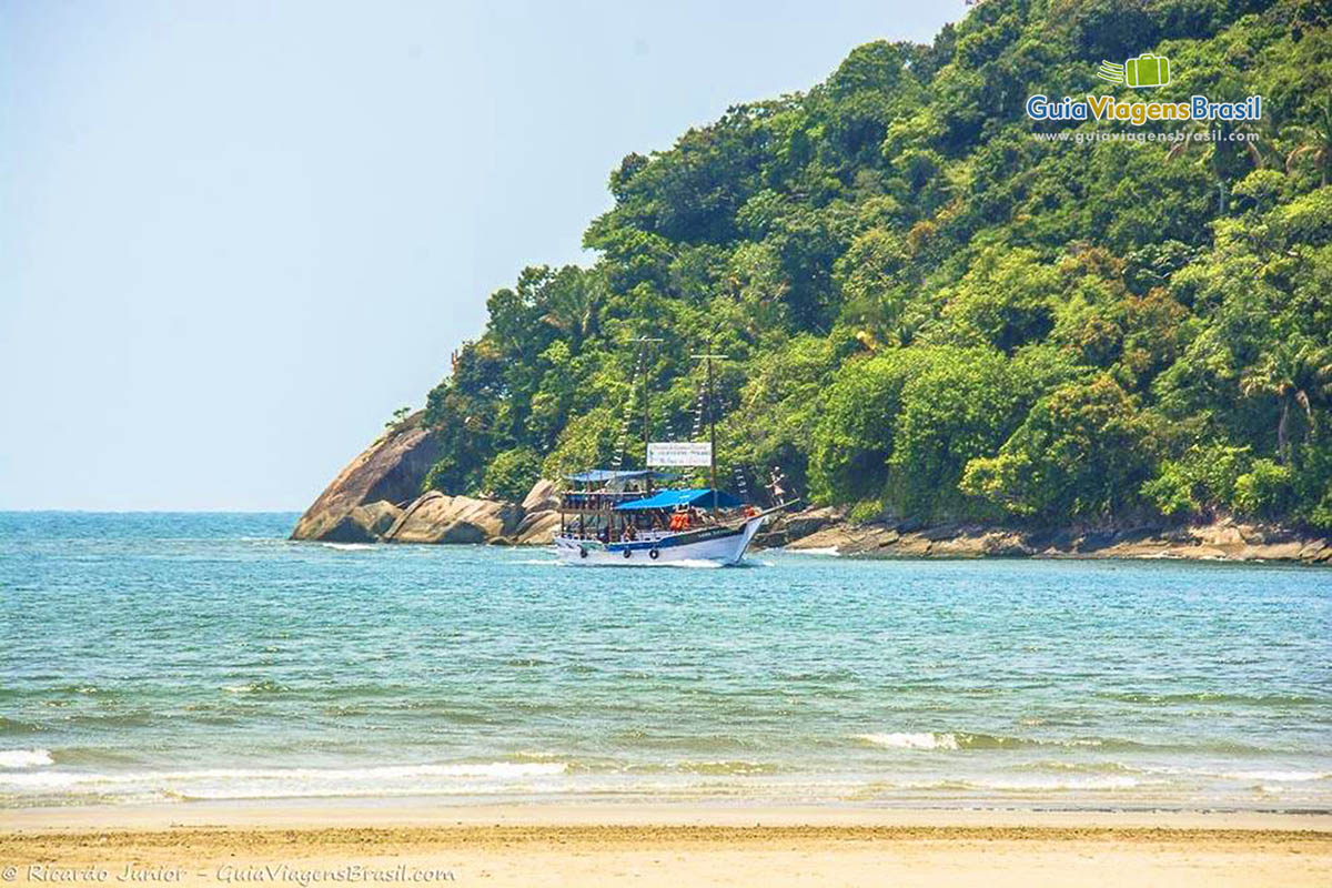 Imagem de um barco de passeio no mar calmo da Praia Enseada.