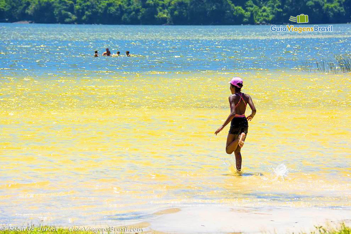 Imagem de menina aproveitando a água morna da lagoa.