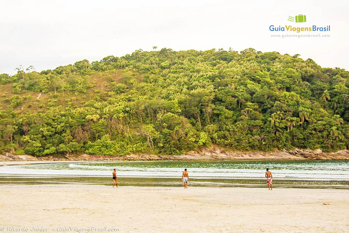 Imagem de três amigos se exercitando na linda praia, no Guarujá.