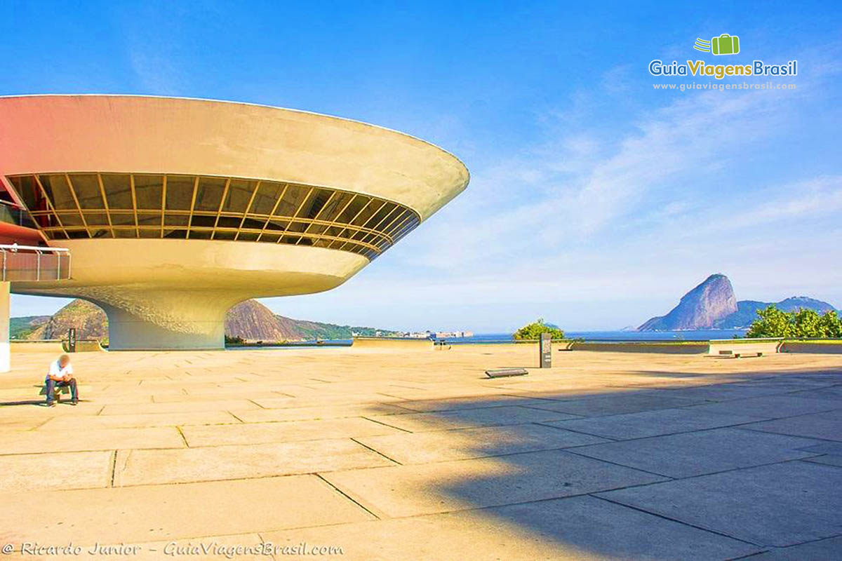 Imagem da bela obra de Oscar Niemeyer e ao fundo paisagem do Rio de Janeiro.