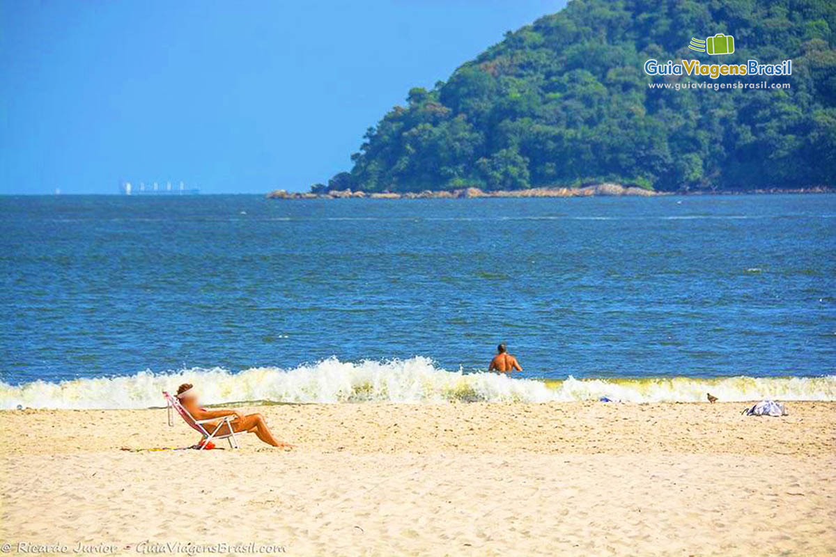 Imagem de uma moça tomando sol a ao fundo as belas ondas da Praia de São Vicente.
