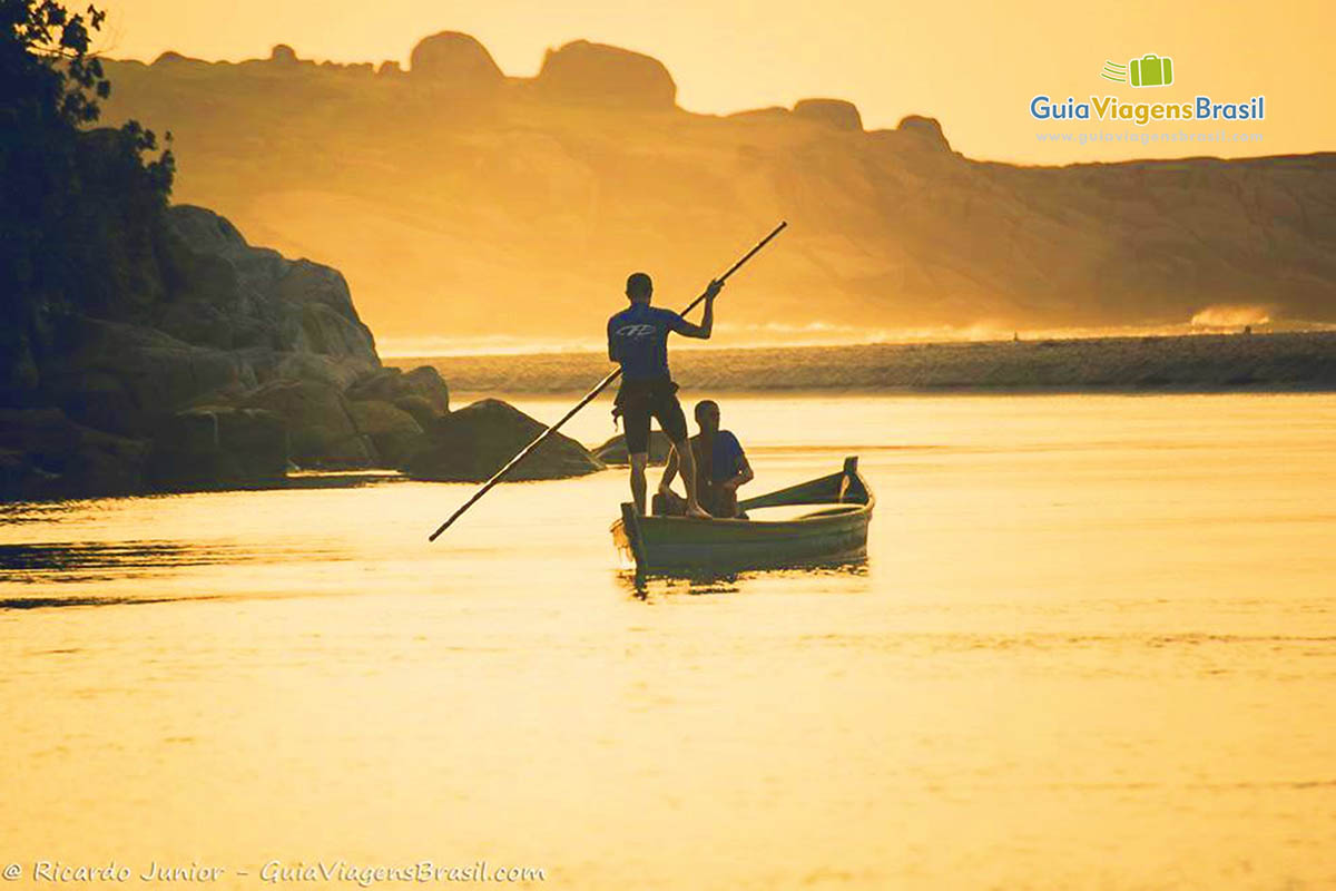 Imagem de pescadores saindo para o mar no fim de tarde.